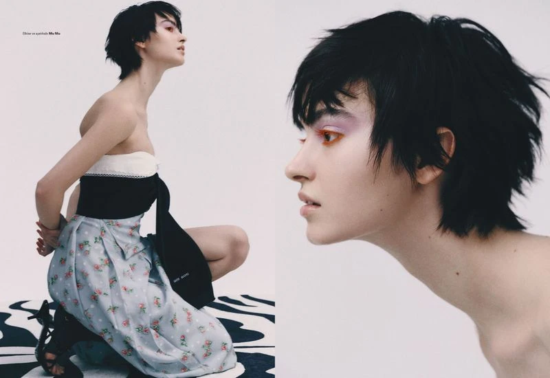 Fashion editorial image featuring an adult female model with short dark hair, makeup, and a floral dress posing in a photo studio.