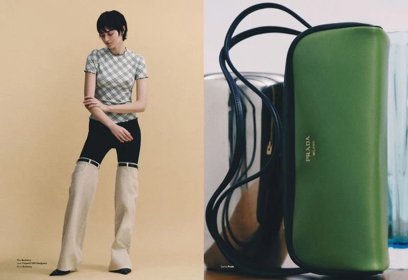 Fashion editorial shot: Woman poses in unique pants and checked top next to a green Prada handbag and silver container indoors.