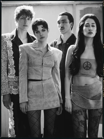 Four fashion models in a black and white studio shot wearing vintage-inspired outfits, with textured stockings and classic hairstyles.