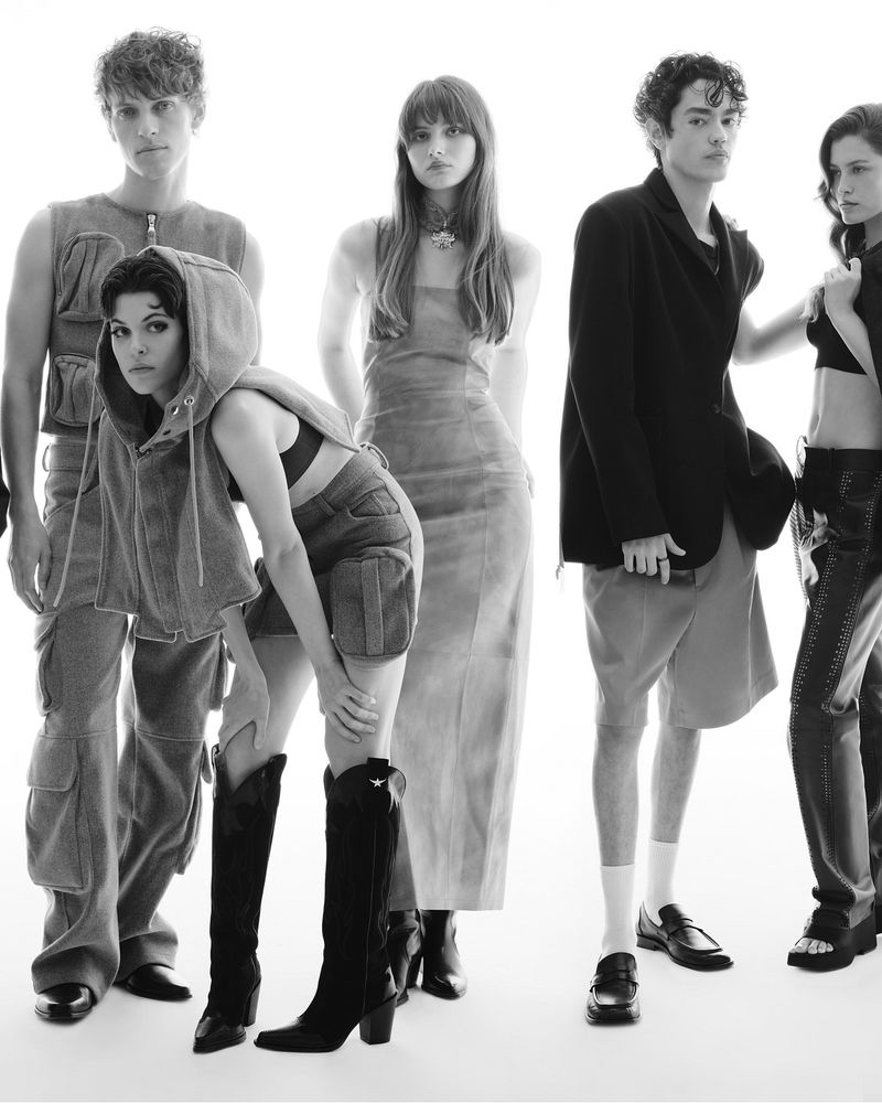Group of fashion models in black and white posing in a photo studio with cargo shorts, black boots and jackets.