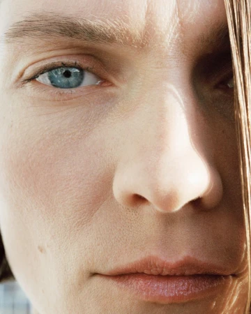 Extreme close-up portrait of model Karolin Wolter highlighting skin texture, a bright blue eye, and natural lighting.