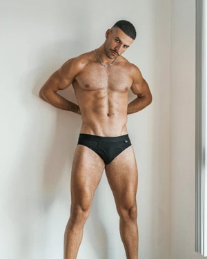 Christopher Lima posing in black briefs against a plain white wall for Yummyzine Issue 8.