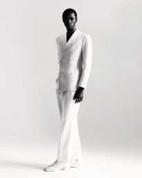 Model Malick Bodian posing in a tailored white double-breasted suit and trousers against a white seamless studio background.