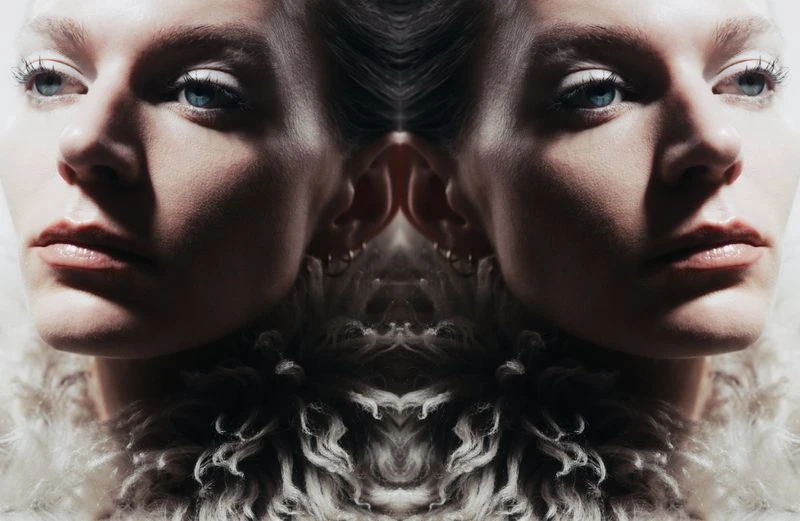 Mirrored close-up portrait of model Bree Naumowicz with blue eyes wearing a textured shearling collar.