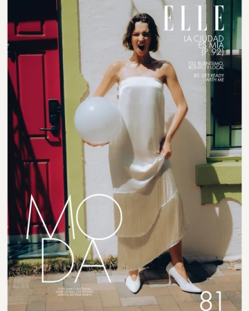 Model Alida Aciu posing with a white balloon in an off-white fringe dress by a red front door for Elle Mexico.