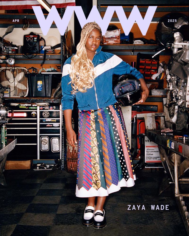 Magazine cover featuring Zaya Wade in a blue jacket and tie skirt, holding a helmet, set against a garage backdrop with tools.