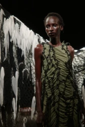 Model wearing a green ruched dress with black trim in a runway show for Pauline Dujancourt S/S 25