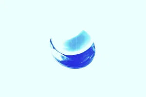 Luminous electric blue translucent curved object resting centrally on an overexposed bright white background.