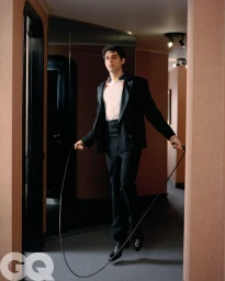 Italian singer Bresh jumping rope in a tailored black suit and white shirt inside an interior hallway for GQ Italia.
