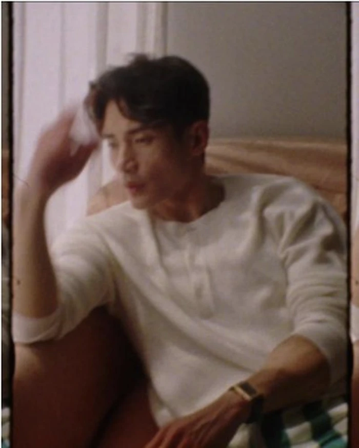 Man wearing a cream long-sleeve shirt sitting indoors near a window with soft natural lighting for InStyle U.S.