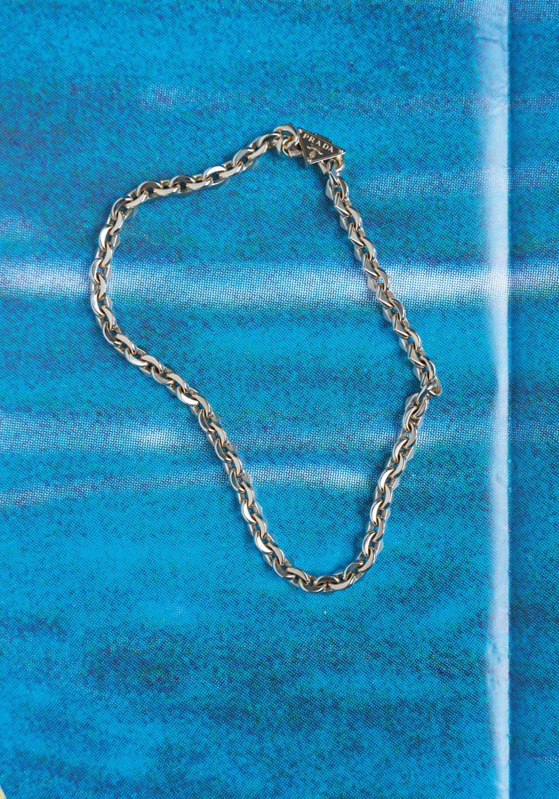 Silver chain necklace on a blue patterned surface. Jewelry fashion shoot. Close-up of elegant necklace.