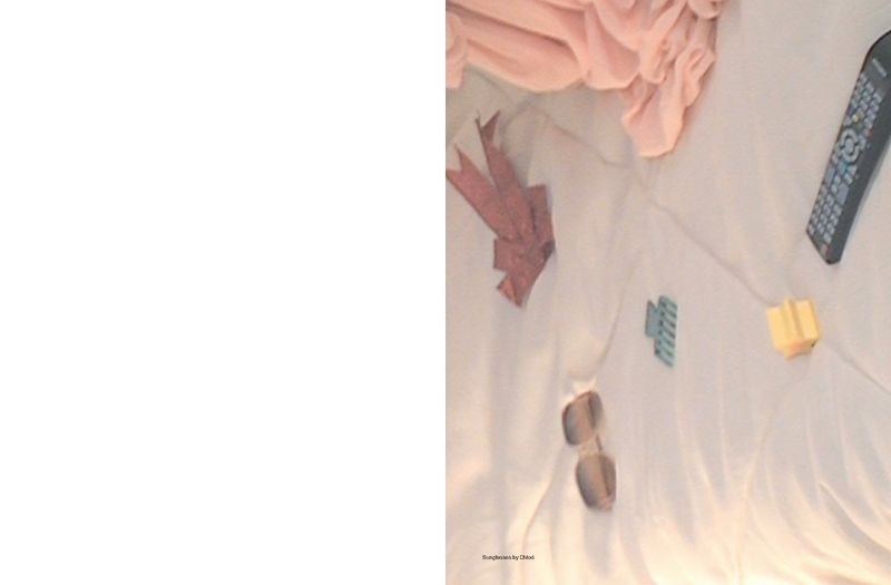 Objects including a TV remote, sunglasses, pink fabric, and other small items are laid out on a white surface.
