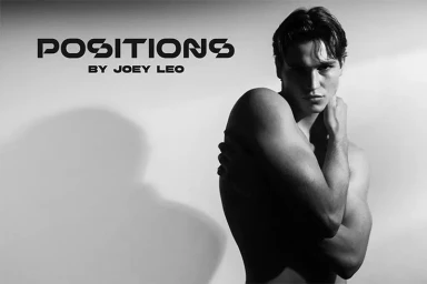 Black and white portrait of a shirtless man posing with arms crossed against a plain light background.
