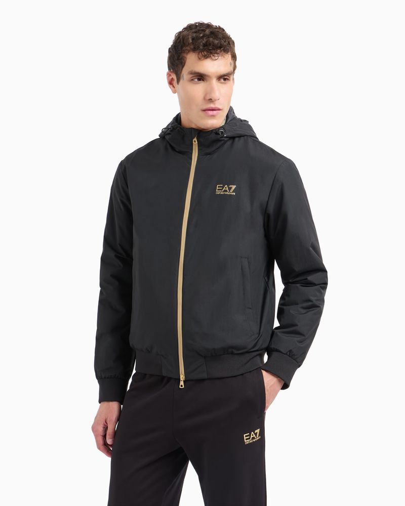 Male model in a black EA7 jacket and sweatpants. Casual fashion shot on a white backdrop with neutral studio lighting.