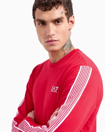 Close-up portrait of a male model wearing a red long-sleeve sweatshirt with white stripe details against a white background.