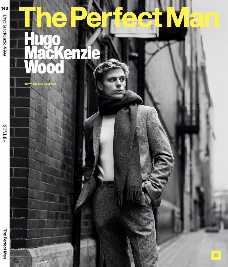 Fashionable blond man in a grey suit and scarf, photographed on a city street for a magazine cover.