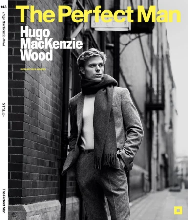 Fashionable blond man in a grey suit and scarf, photographed on a city street for a magazine cover.