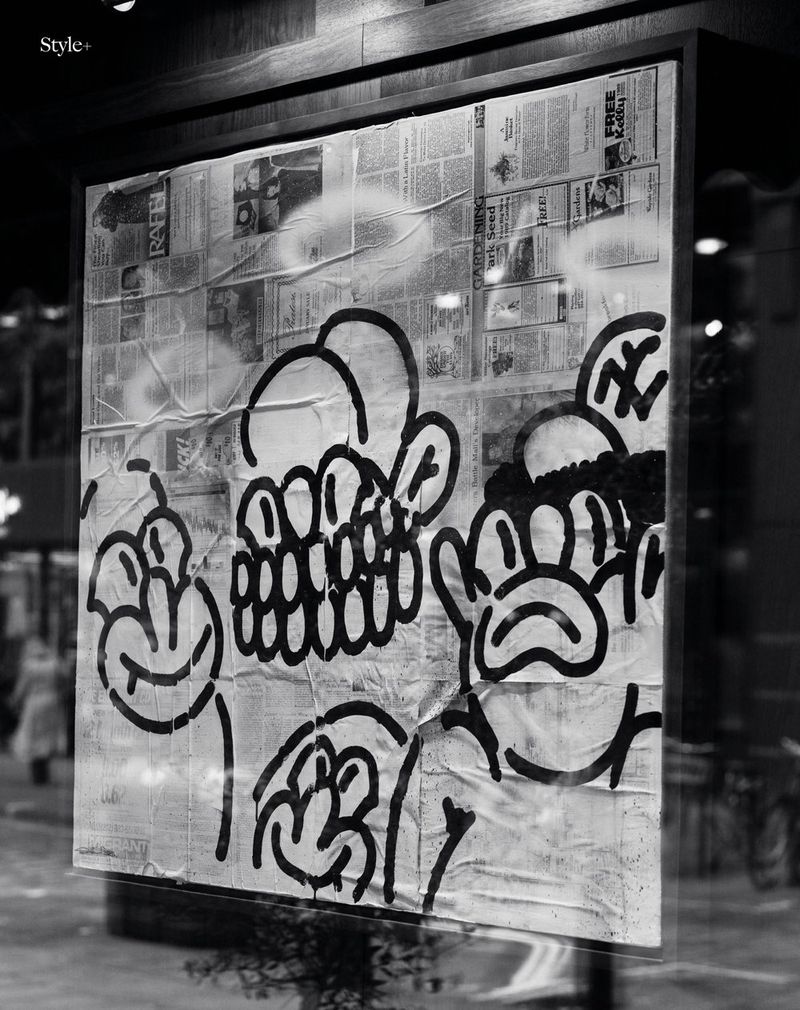 Monochrome display of line art on newspaper in a window, reflecting an urban setting, capturing a blend of art and city life.