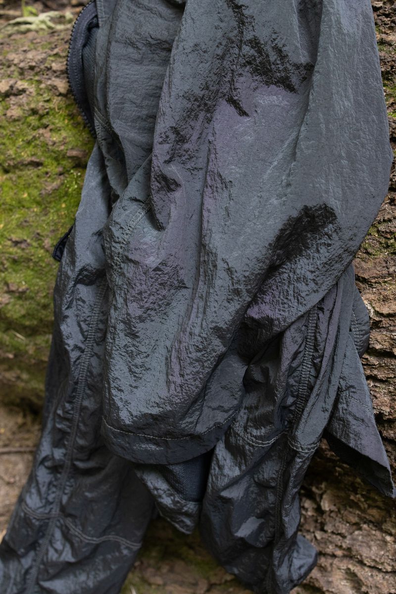 Wrinkled black and grey jacket draped over textured tree bark, close-up studio shot emphasizing texture and color variations.