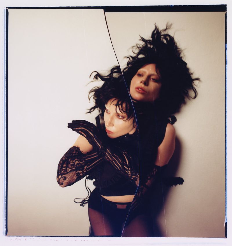 Unique portrait of a young adult woman with an identical reflection, styled with black lace gloves and an elaborate black hairstyle in a photo studio.