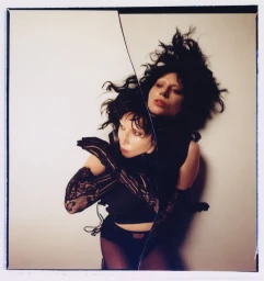 Lady Gaga in black lace gloves and dark top posing against a plain background in a split-frame portrait shot by Frank Lebon.