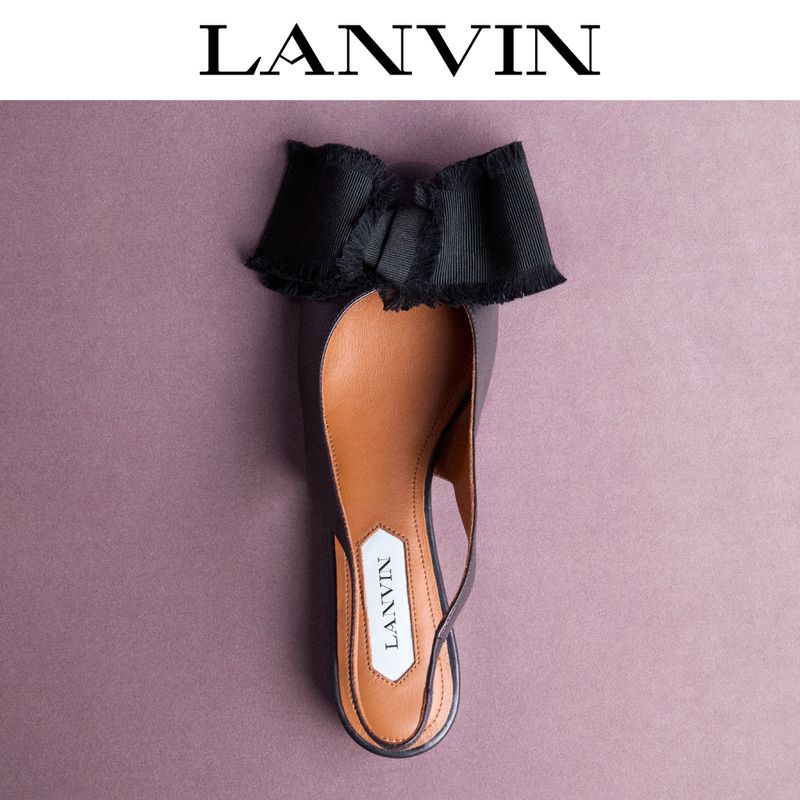 Elegant Lanvin slingback flat with a black bow on a pink background. Shoe with black exterior, tan interior and a logo tag.