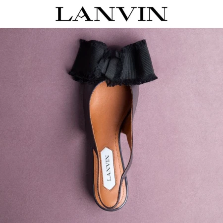 Elegant Lanvin slingback flat with a black bow on a pink background. Shoe with black exterior, tan interior and a logo tag.