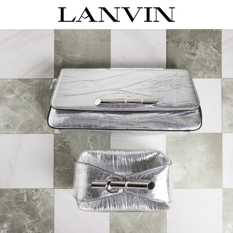 Two metallic silver Lanvin handbags with a metal bar detail are set against a checkered grey and white tile background, product shot.