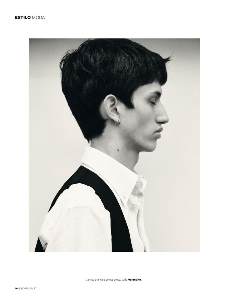 Black-and-white portrait of a young adult man with dark hair in profile wearing a white button-down shirt and black vest indoors.