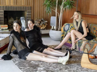 Three female musicians of Haim seated in a mid-century modern living room for an Interview Magazine feature
