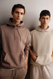 Two male models posing against a neutral grey studio background wearing casual hoodies and sweatpants