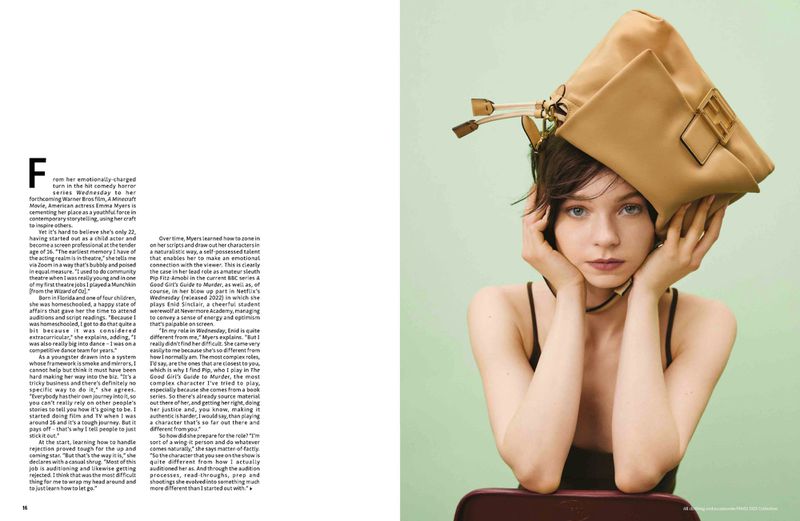 Brunette woman with a tan leather purse on her head posing in a studio against a green wall, showcasing a playful fashion editorial.