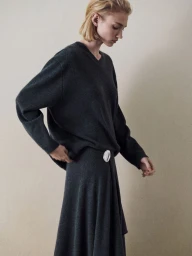 Model Tess Breeden wearing a charcoal grey cashmere sweater and matching skirt against a neutral studio backdrop.