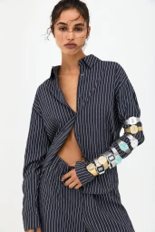 Model wearing a navy pinstripe shirt and matching trousers, with multiple digital watches stacked along her arm against a white background.