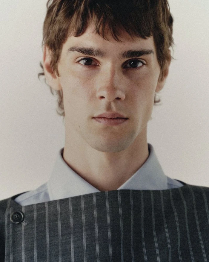 Portrait of male model Patryk Lawry wearing a pinstripe top and light shirt for Kyle'Lyk F/W 25 Collection by Justin von Oldershausen