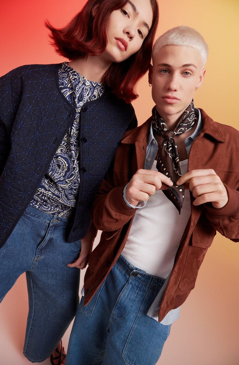 Two young adults in fashionable casual wear, standing indoors against a gradient background; a quilted jacket and bandana are featured.