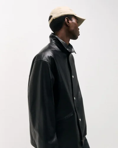 Model wearing a black leather jacket and beige cap against a plain white background for Bally Pre-Fall 2025 lookbook.