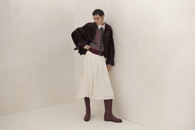 Fashion shot of a woman in a fur jacket, striped top, and white skirt, accessorized with knee-high boots, posing against a neutral backdrop.