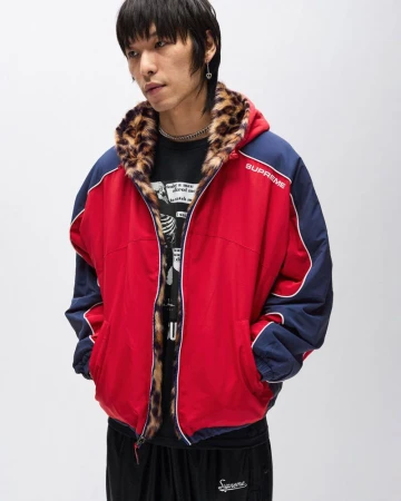 Asian male model in red and blue reversible jacket with leopard print trim, paired with black sweatpants in a neutral indoor setting.