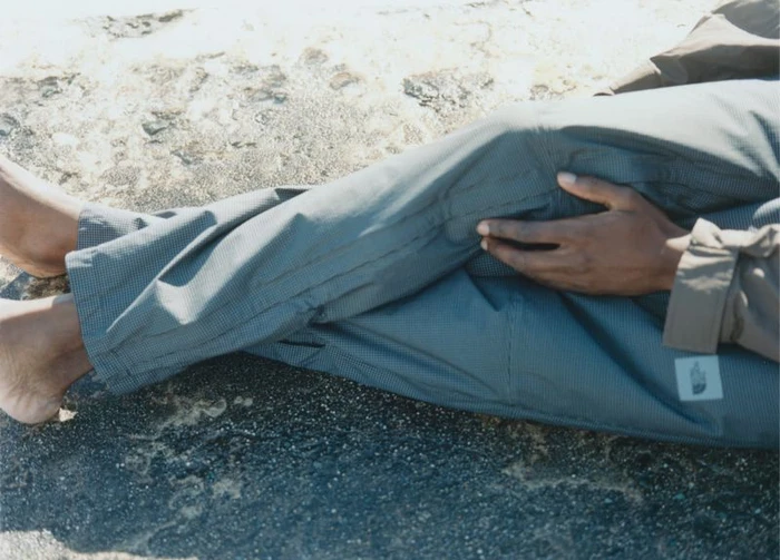 Close-up of a person reclining on rocky terrain wearing patterned grey trousers and a jacket by The North Face.