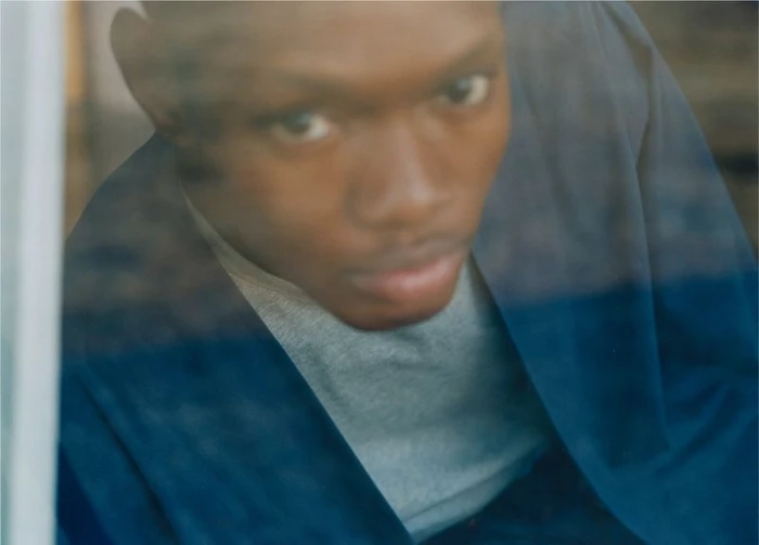 Close-up portrait of a Black man looking through a window with reflections for The North Face by Rebekka Deubner