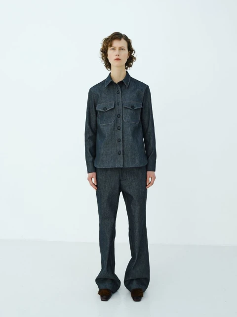Full-length shot of a young woman in a button-down denim shirt and denim pants in a white studio setting. Fashion photography.