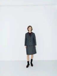 Model wearing a dark blazer and matching skirt against a plain white studio background
