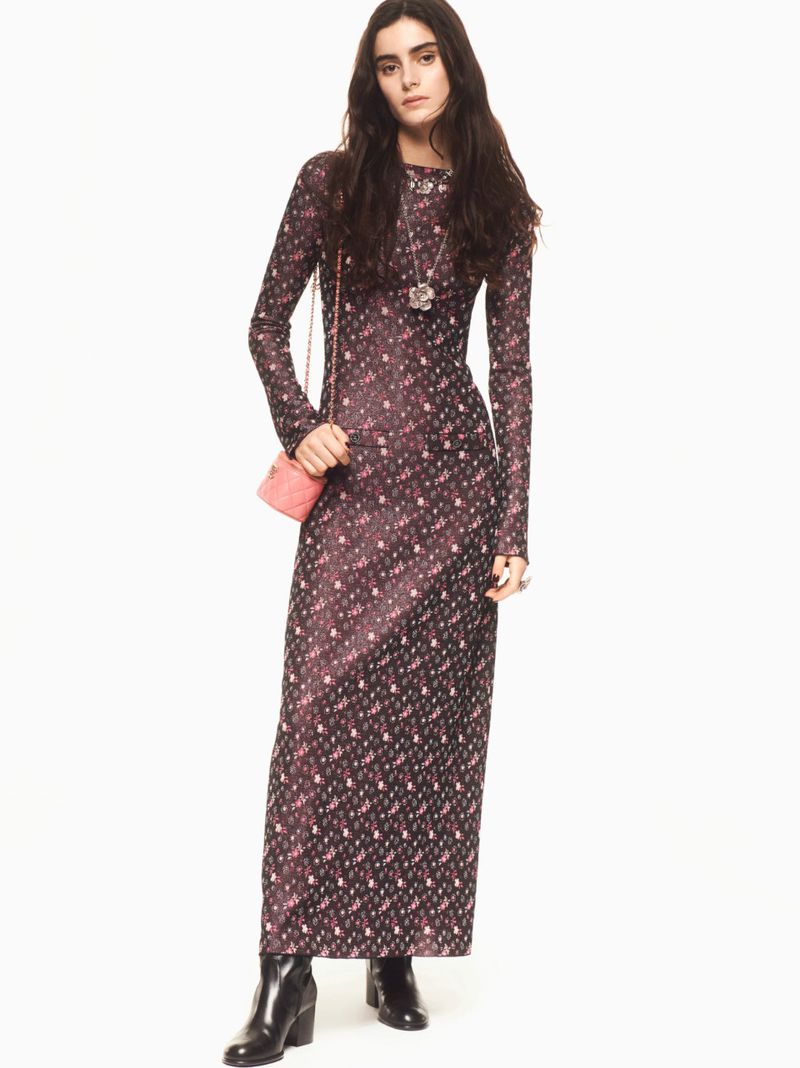 Model wearing a dark floral long sleeve dress with black boots and a small pink quilted crossbody bag