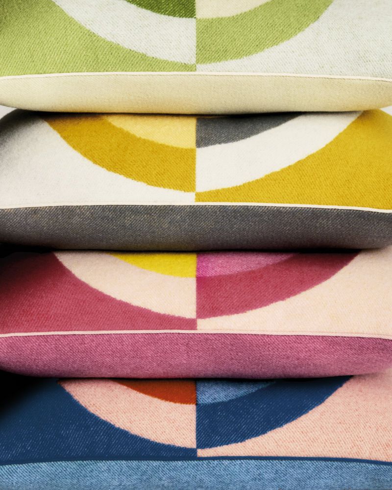 Stack of colorful textured pillows with semi-circle pattern, indoor setting, interior decor. Soft pastel shades create a cozy home vibe.