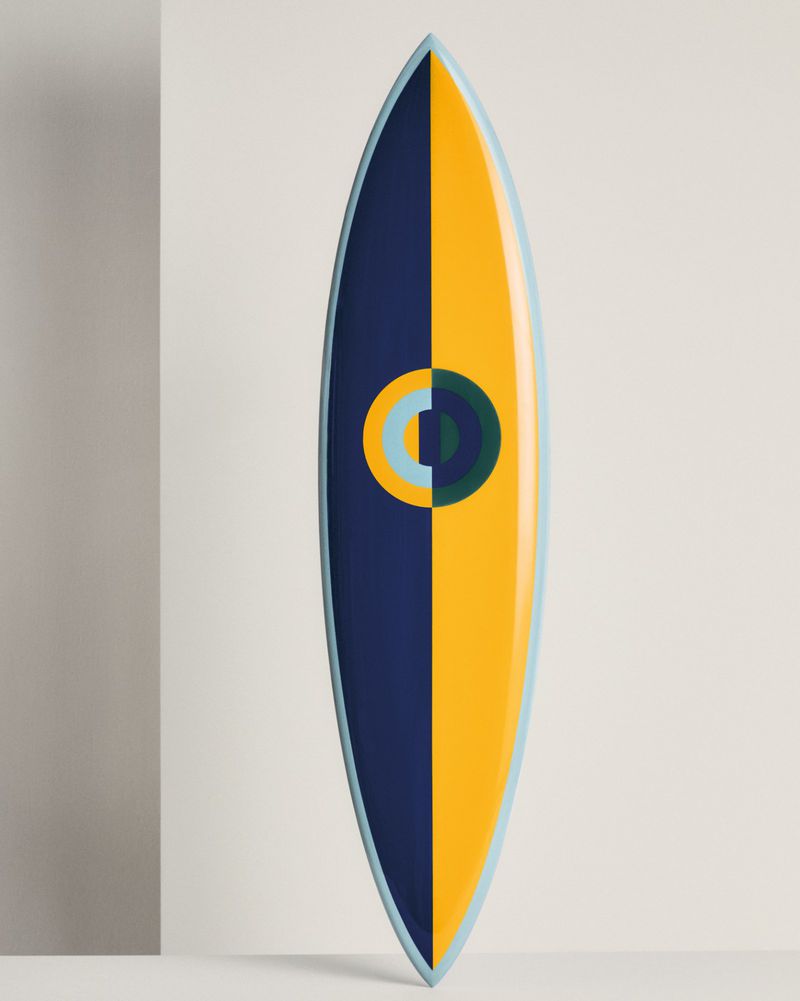 Surfboard with a split design of navy blue and yellow, featuring a circular design with shades of blue and green on a white backdrop.