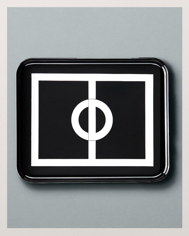 Black tray featuring a white geometric pattern with a circle bisected by a line, complemented by a gray background, creating a modern design.