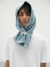 Model Max Everist wearing a white t-shirt with a light blue striped towel wrapped around his head against a white backdrop.