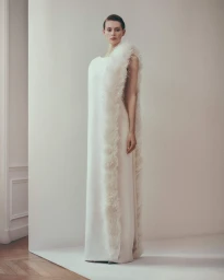 Model Lauren de Graaf wears a sleeveless ivory column gown with feathered trim for Ashi Studio 8PM Collection.