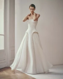 Model Lauren de Graaf wearing a strapless white beaded couture gown by Ashi Studio against a neutral studio backdrop.